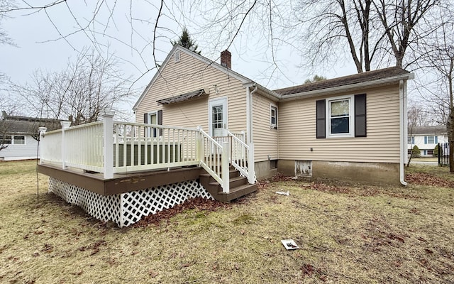 back of house featuring a yard, a chimney, and a wooden deck