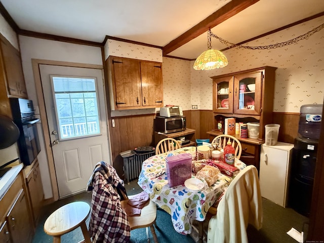 dining space featuring crown molding, wood walls, wainscoting, and wallpapered walls