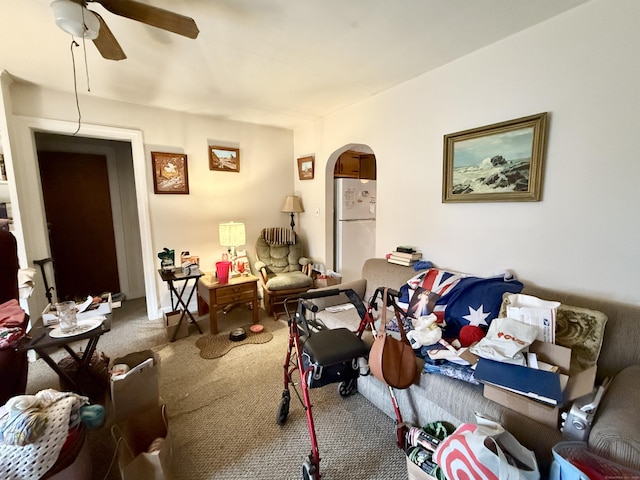 carpeted living room featuring arched walkways and ceiling fan