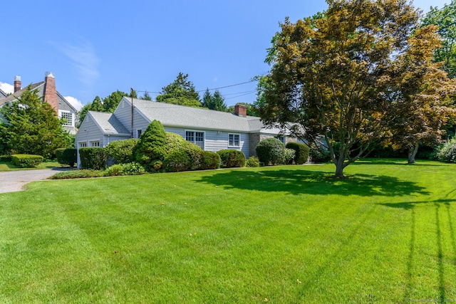 view of front of property with a chimney, a front lawn, and gravel driveway