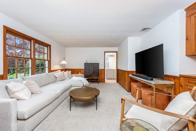living area featuring visible vents, wainscoting, wooden walls, and light colored carpet