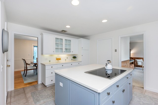 kitchen featuring visible vents, black electric cooktop, light countertops, glass insert cabinets, and white cabinetry