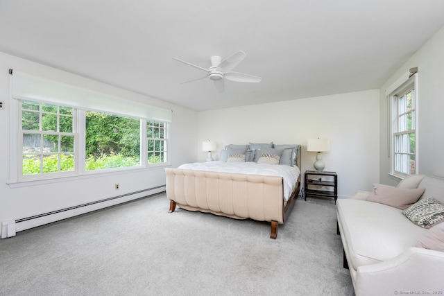 carpeted bedroom with a baseboard radiator, a ceiling fan, and multiple windows