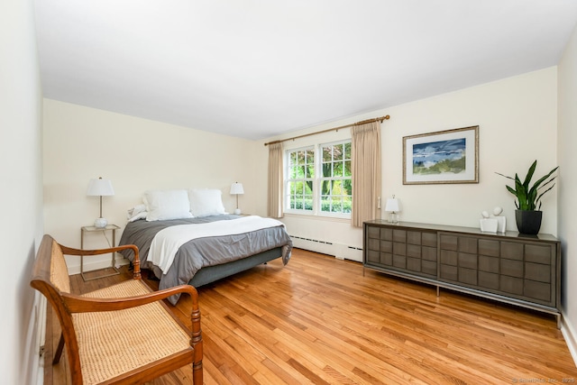 bedroom with light wood-type flooring and a baseboard radiator
