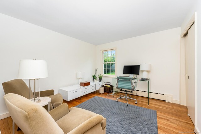 office space with a baseboard heating unit and light wood-style flooring