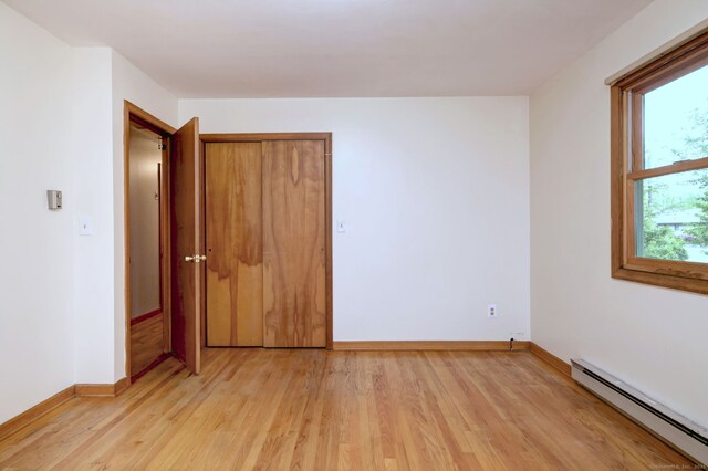 478 Alpom Dr, Orange, CT 06477 - unfurnished bedroom with a baseboard heating unit, light wood-type flooring, baseboards, and a closet