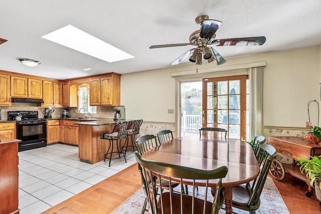 101 Michele Dr, Somers, CT 06071 - kitchen featuring ceiling fan, a peninsula, black range with electric cooktop, under cabinet range hood, and a skylight