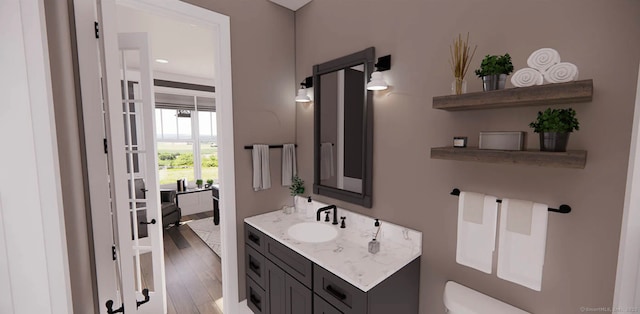 half bathroom featuring vanity, wood finished floors, and toilet