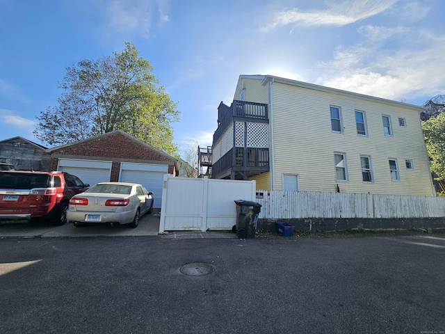 view of side of property featuring fence, an outbuilding, and a detached garage
