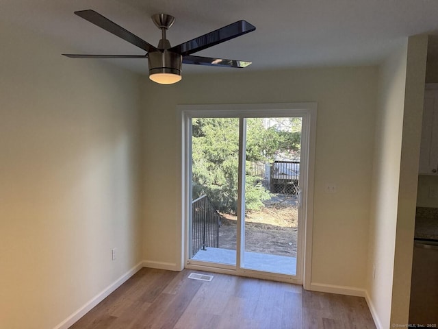 interior space with baseboards, a ceiling fan, wood finished floors, and visible vents