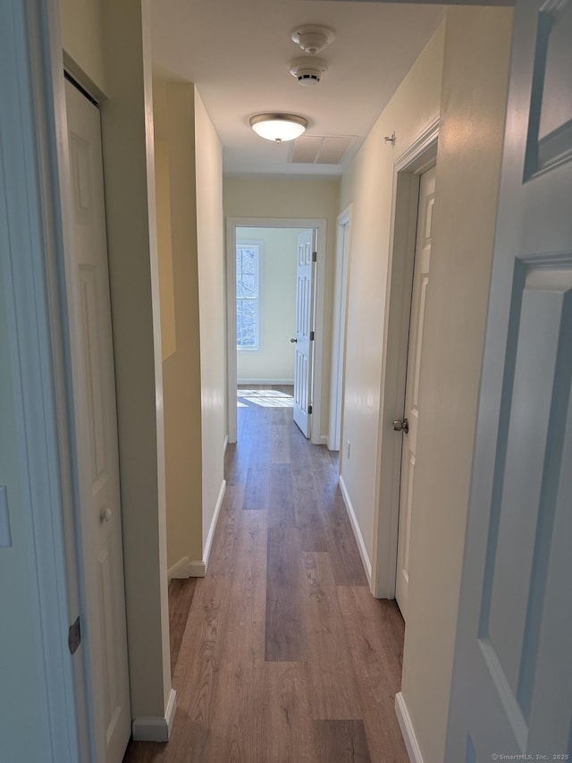 corridor with baseboards and wood finished floors
