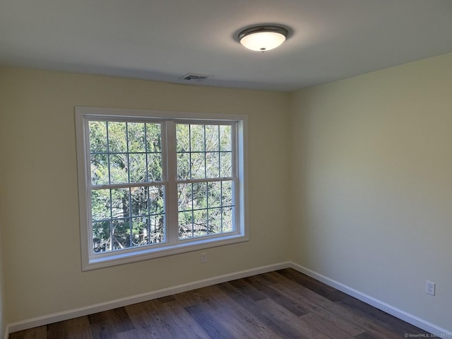 unfurnished room with baseboards, dark wood-style flooring, and visible vents