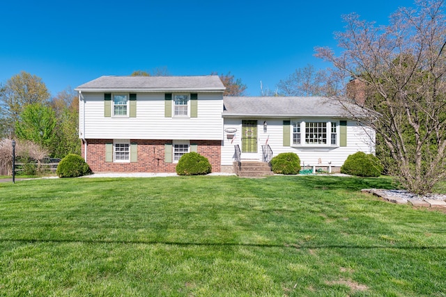 tri-level home with brick siding, a chimney, and a front yard