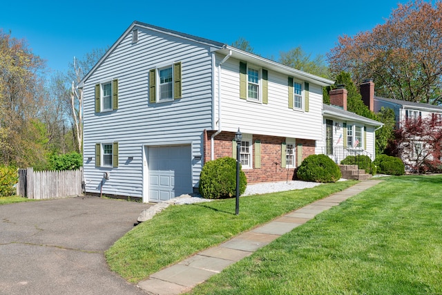 split level home featuring brick siding, a garage, aphalt driveway, and a front yard