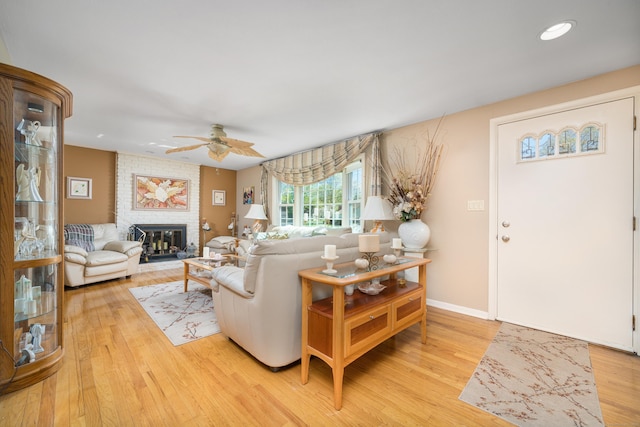 living area with a fireplace, baseboards, ceiling fan, light wood-type flooring, and recessed lighting