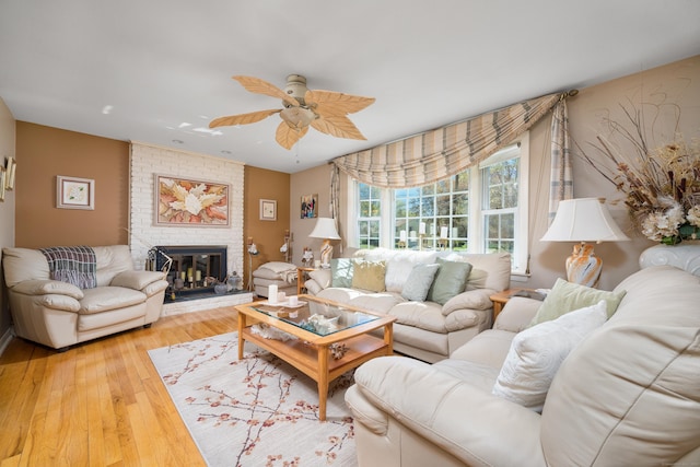 living area with ceiling fan, hardwood / wood-style flooring, and a fireplace