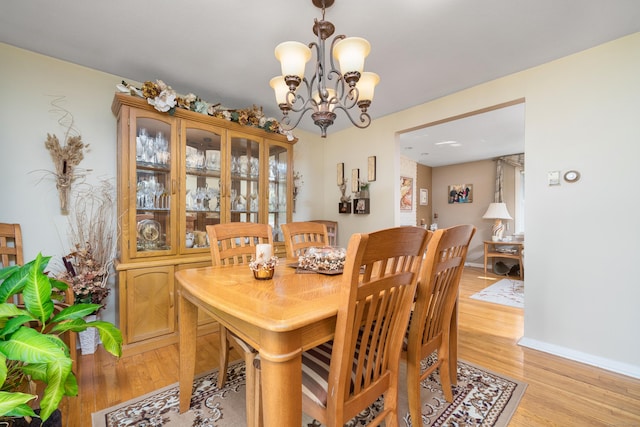 dining space featuring baseboards, a notable chandelier, and light wood-type flooring