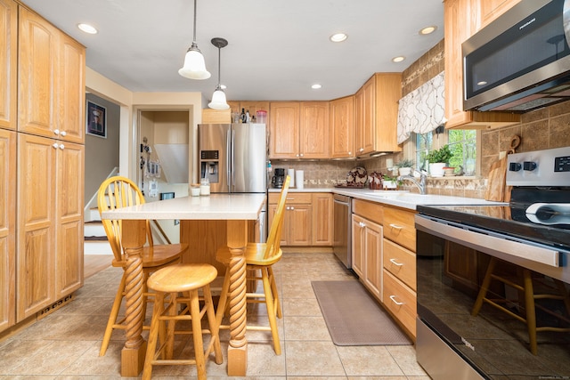 kitchen featuring decorative backsplash, a kitchen island, a kitchen bar, light countertops, and stainless steel appliances