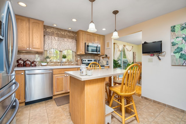 kitchen featuring light countertops, appliances with stainless steel finishes, a kitchen breakfast bar, and backsplash