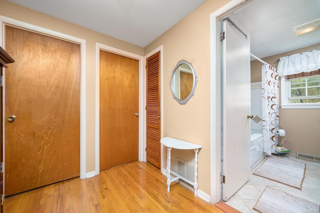 foyer entrance featuring baseboards, hardwood / wood-style floors, and visible vents