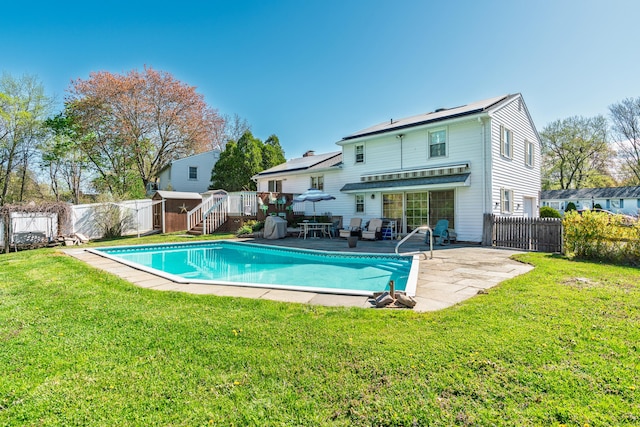 back of property featuring a yard, a deck, a fenced in pool, and a fenced backyard