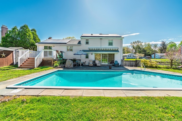 rear view of property with a yard, a deck, an outdoor pool, and a fenced backyard