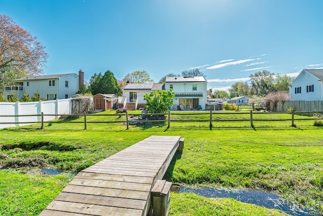 surrounding community with a storage shed, a fenced backyard, a yard, and a residential view
