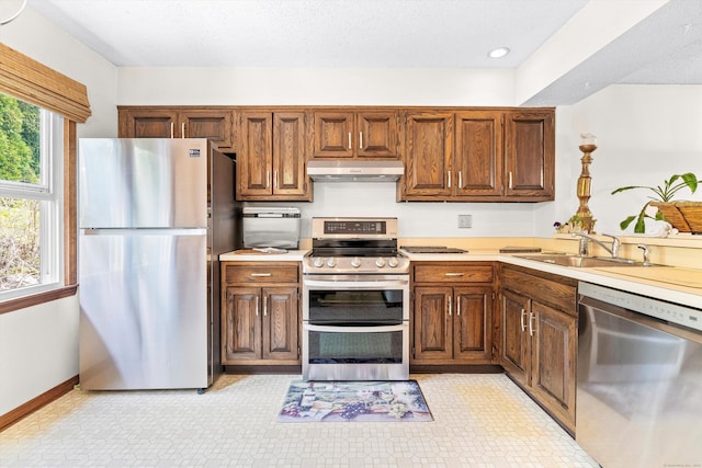 55 Mill Plain Rd Unit 8-1, Danbury, CT 06811 - kitchen featuring stainless steel appliances, under cabinet range hood, light countertops, brown cabinets, and recessed lighting