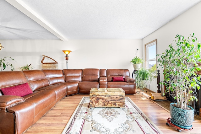 living area with a textured ceiling, wood finished floors, and beam ceiling