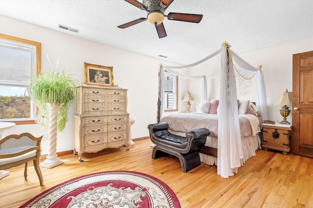 bedroom featuring visible vents, a textured ceiling, ceiling fan, and light wood-type flooring