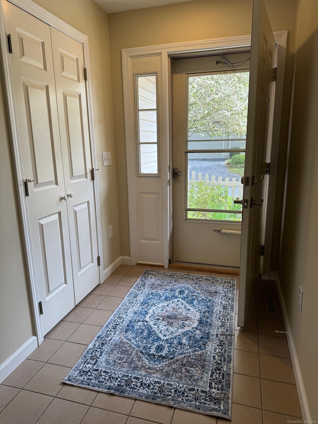 doorway featuring baseboards, light tile patterned floors, and a wealth of natural light