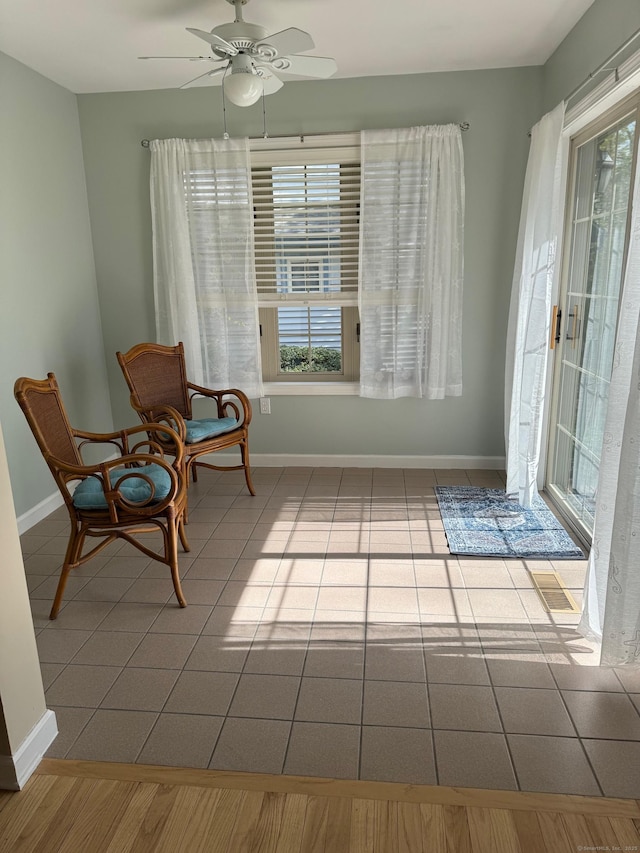 sitting room with baseboards, tile patterned flooring, and a ceiling fan