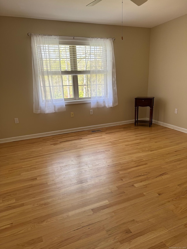 empty room with baseboards, visible vents, and light wood-type flooring