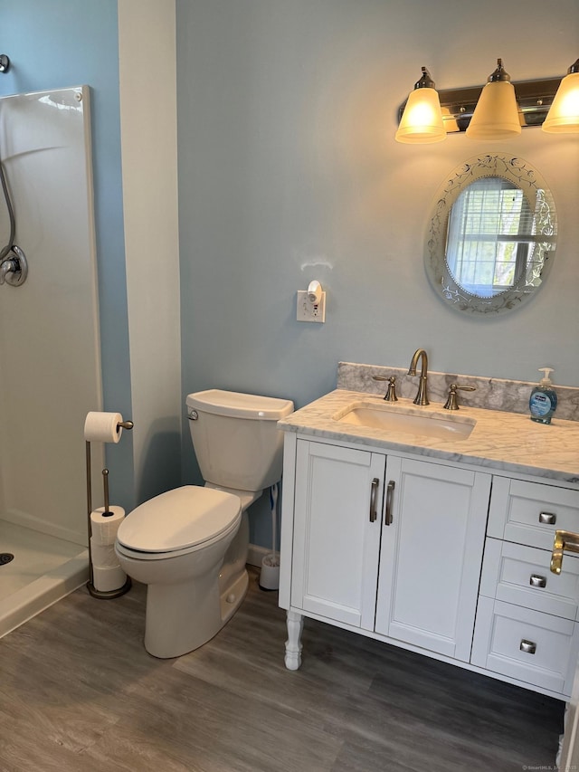 full bath with vanity, wood finished floors, toilet, baseboards, and walk in shower