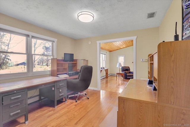 office with baseboard heating, visible vents, plenty of natural light, and light wood-style flooring