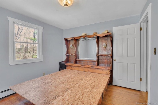 bedroom featuring wood finished floors and baseboard heating