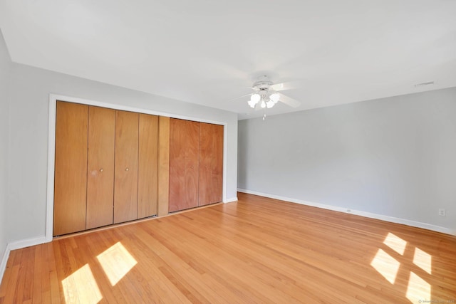 unfurnished bedroom featuring visible vents, a closet, light wood-style floors, baseboards, and ceiling fan