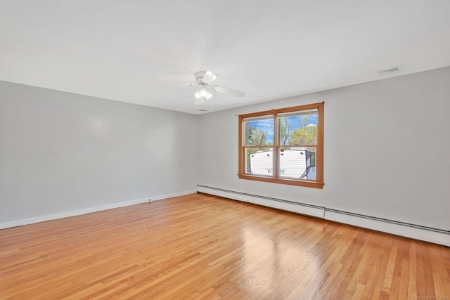 spare room featuring light wood-style flooring, a ceiling fan, baseboards, a baseboard radiator, and visible vents