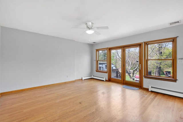 empty room featuring a ceiling fan, visible vents, baseboard heating, baseboards, and light wood-style flooring