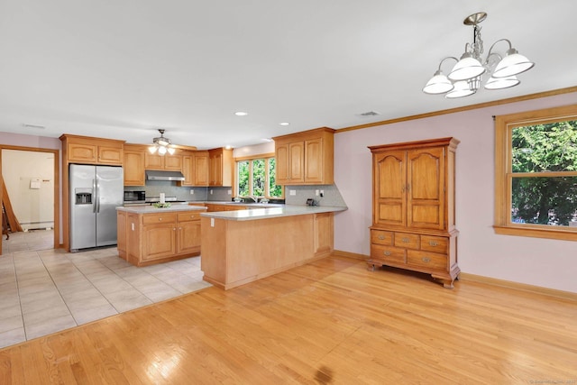 kitchen featuring light countertops, light wood-style flooring, stainless steel appliances, backsplash, and under cabinet range hood