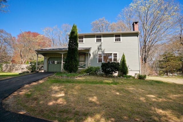 traditional-style house with a garage, a chimney, driveway, and a front yard