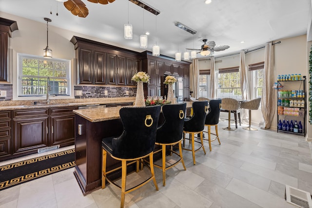 bar with a healthy amount of sunlight, decorative backsplash, a ceiling fan, visible vents, and a sink