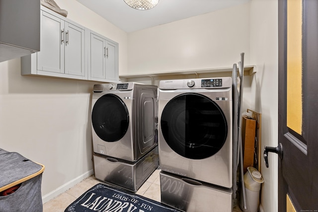 laundry area with baseboards, cabinet space, light tile patterned flooring, and washer and dryer