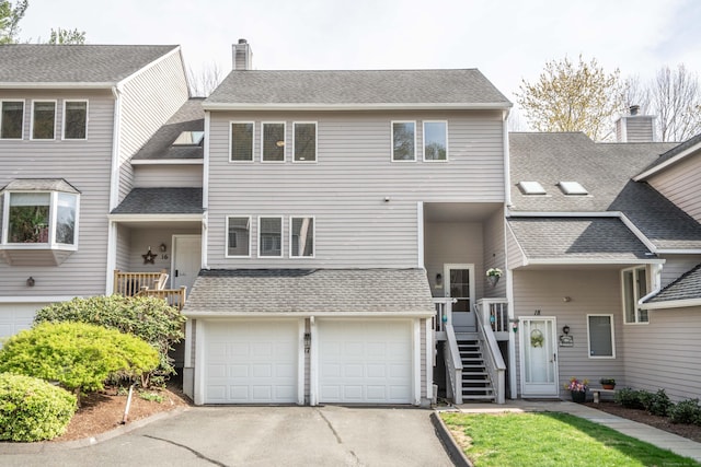 multi unit property with a chimney, stairway, aphalt driveway, an attached garage, and a shingled roof