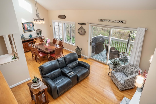 living area with baseboards, vaulted ceiling, and light wood-style flooring