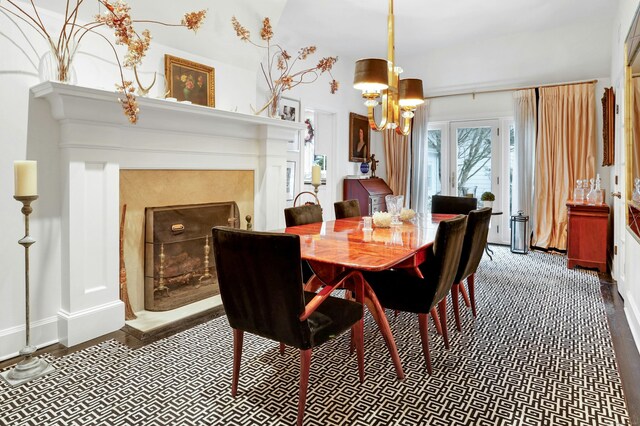 dining area featuring baseboards, a fireplace, wood finished floors, and a chandelier