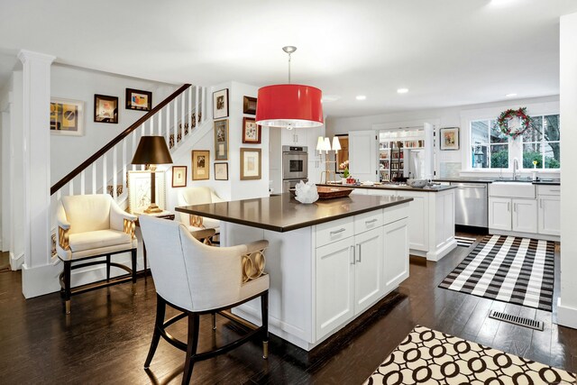 kitchen featuring a kitchen island, dark countertops, dark wood-style floors, white cabinetry, and dishwasher