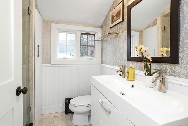 bathroom with toilet, vaulted ceiling, wainscoting, and vanity