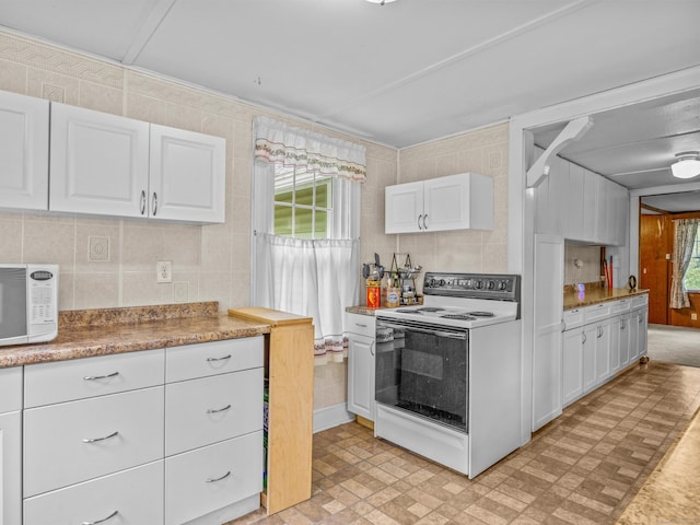 kitchen with white appliances, plenty of natural light, white cabinetry, decorative backsplash, and tile walls