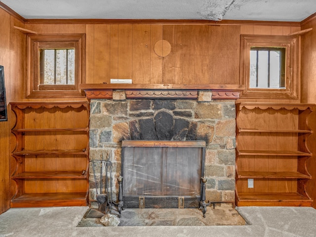 detailed view of a fireplace, carpet flooring, wood walls, and crown molding